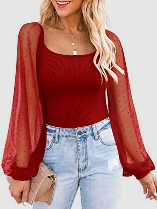 Ribbed Red blouse with sheer polka dot long lantern sleeves worn by a model with long blonde hair wearing light blue denim against a white background.