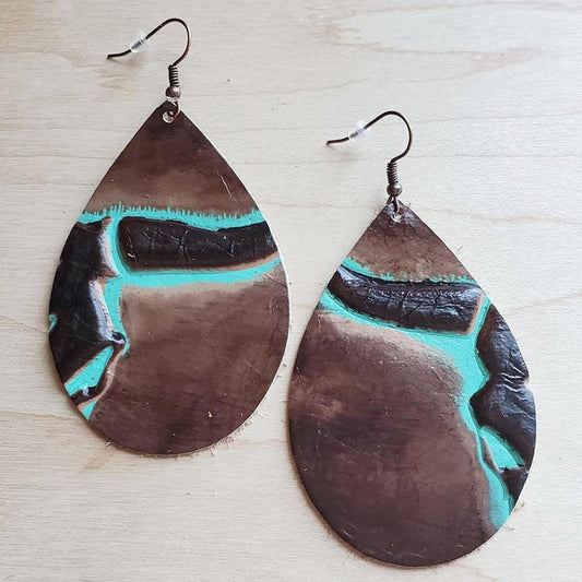 Genuine Leather earrings in with a side steer head pattern in brown and turquoise shown on a wooden table.
