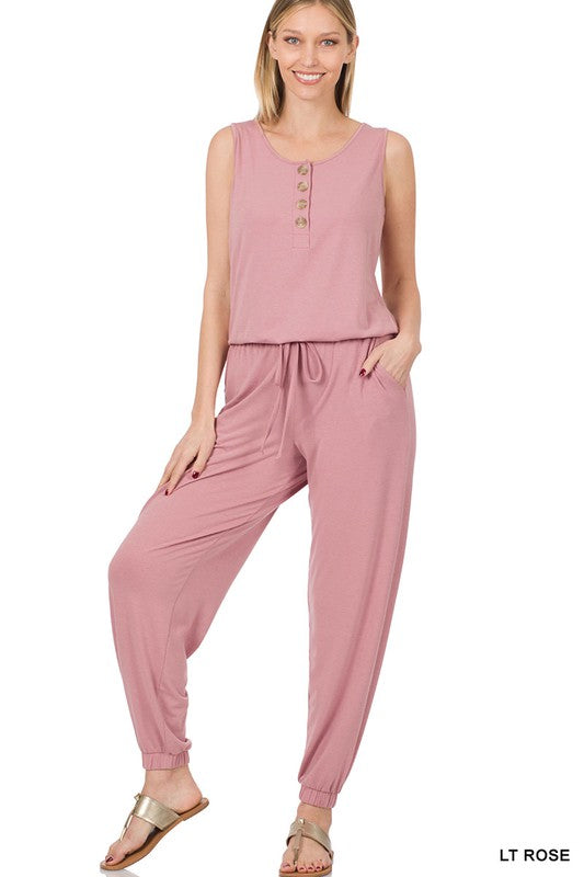 Blonde model wearing a light rose sleeveless jogger pant jumpsuit with button detail.