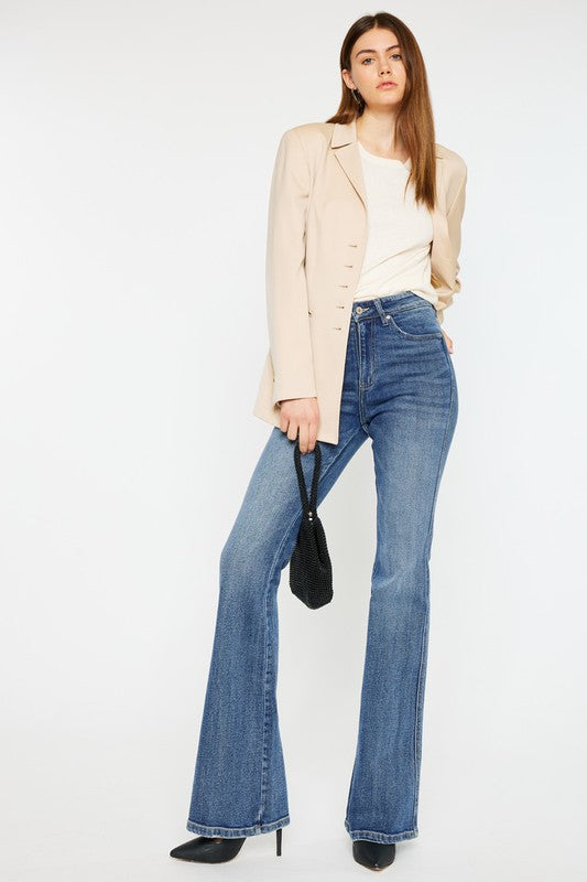 Brunette model wearing a tan blazer with a white top and the Kancan high rise flare jeans with black heels.
