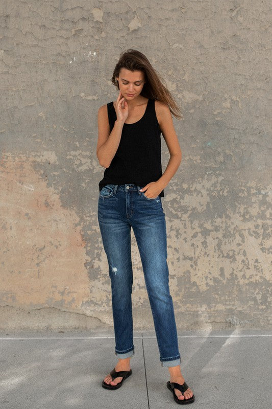 Brunette model wearing a black tank and flip flops featuring cuffed stretch skinny jeans in dark wash.