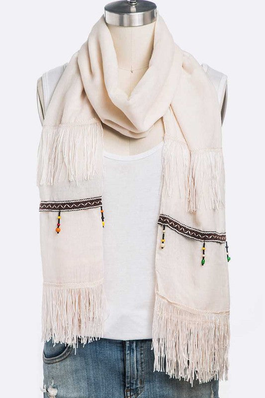 Beige oblong scarf with fringe ends and tassel details in beige.