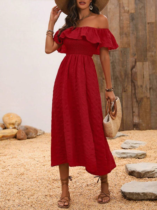 Brunette model in a rock garden wearing a red-rust front slit, off-shoulder, midi dress with an elastic waist.