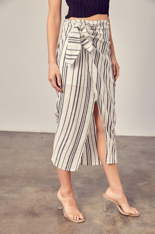 Model wearing heels and a belly shirt with the stripe overlap tie waist skort in ivory with black stripes.