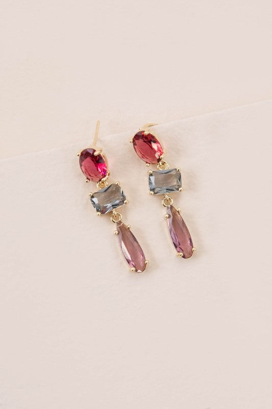 Three stone dangle earrings with magenta, ice blue, and mauve crystals accented by gold in a drop form.