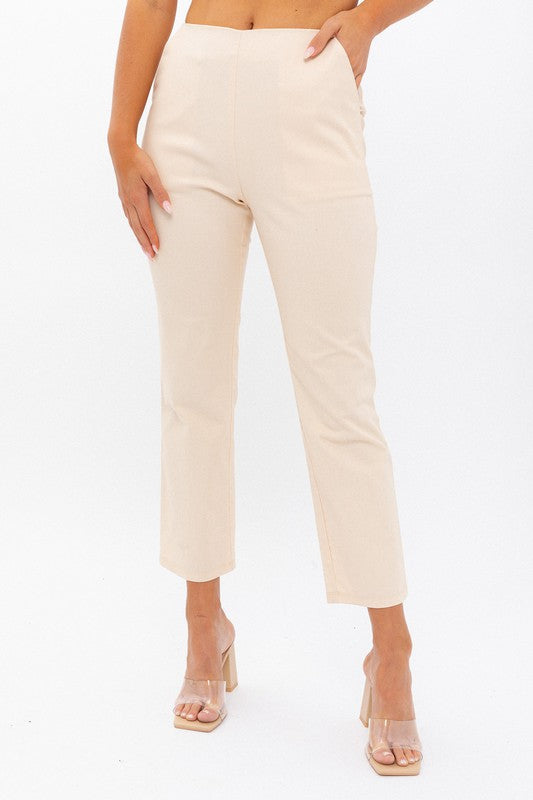 Cream colored high waisted crop leg pants with pockets against a white backdrop