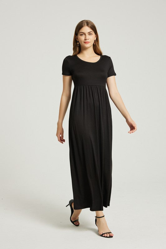 Brunette model wearing a black short sleeve maxi dress with pockets against a white backdrop.