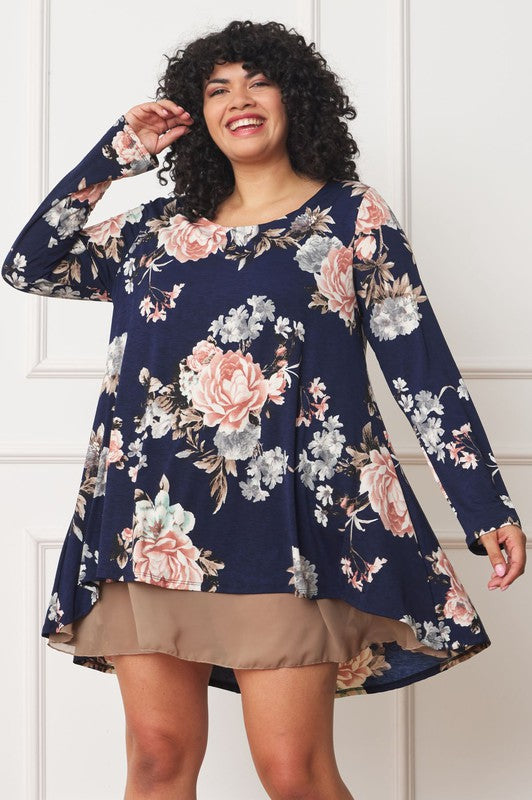 Brunette plus size model wearing a double-layer chiffon dress with long sleeves in navy blue with light pink flowers.