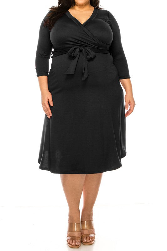 Super stretchy and soft plus size solid color faux wrap dress in black worn by a brunette model against a white backdrop.