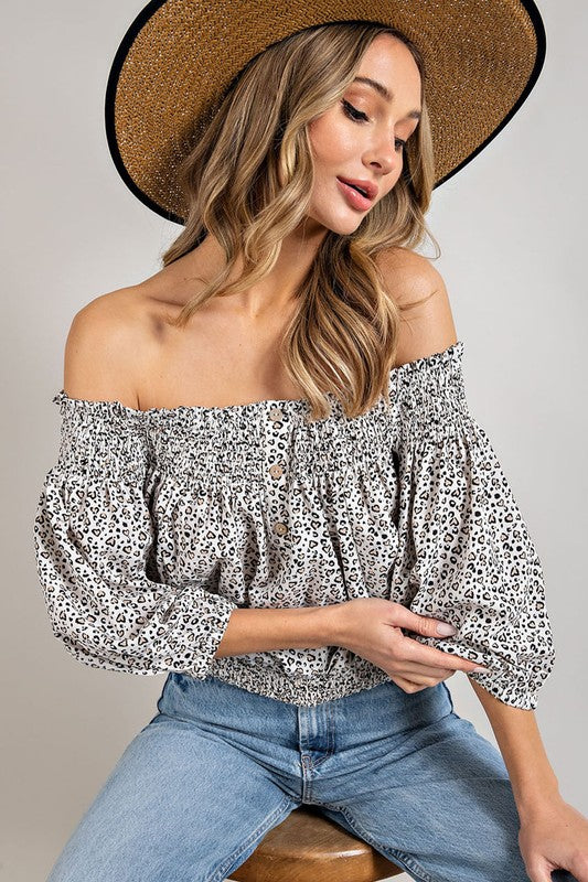 Blonde model wearing a straw hat and jeans with a animal print, off shoulder top.