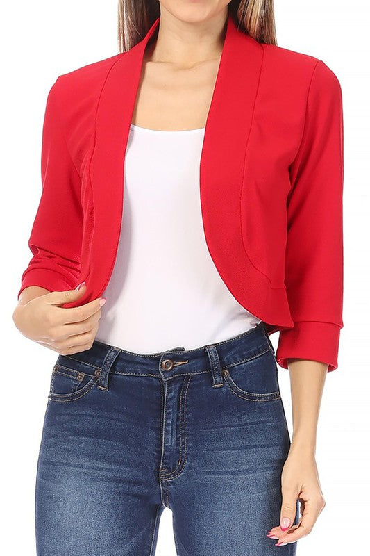 Model wearing a Moa Collection waist length collarless open front blazer in red with jeans and a white top.
