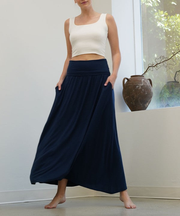 Model wearing a bamboo yoga maxi skirt in navy against a white wall and window.