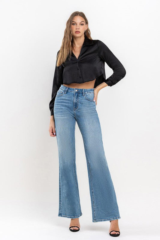 Model wearing a black satin shirt and heels with the high rise wide leg jeans.