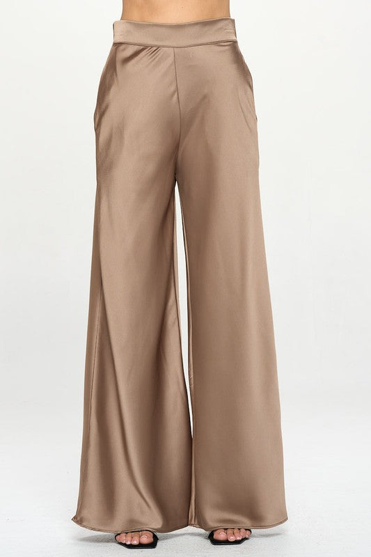 Dressy satin stretch pants with wide leg, elastic waist, and pockets in tan, against a white background