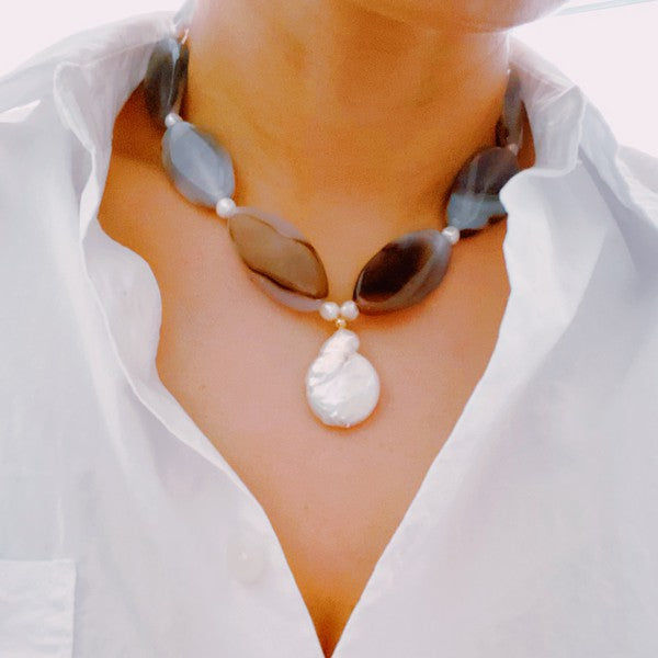 Baroque pearl and natural stone statement necklace made of ethically-sourced components on a model wearing a white shirt.