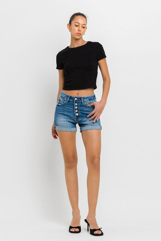 Brunette model wearing a black tee shirt and kitten heels with super high rise button up mom shorts. 