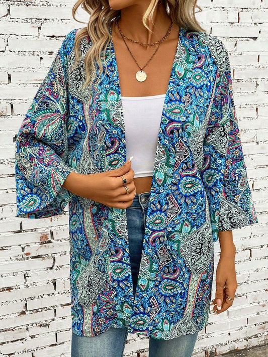 Blonde model wearing a white top and jeans with a teal paisley printed kimono with three-quarter sleeves.