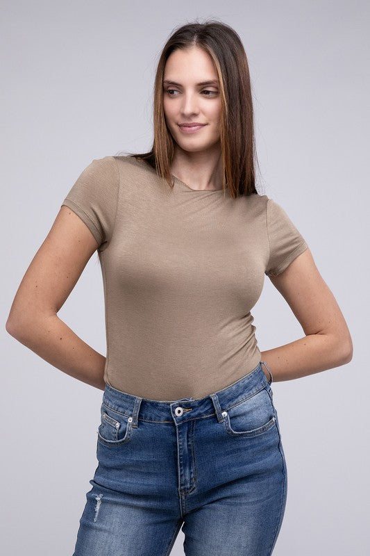 Model with dark hair wearing jeans and a double layered cap sleeve bodysuit in mocha against a white backdrop.