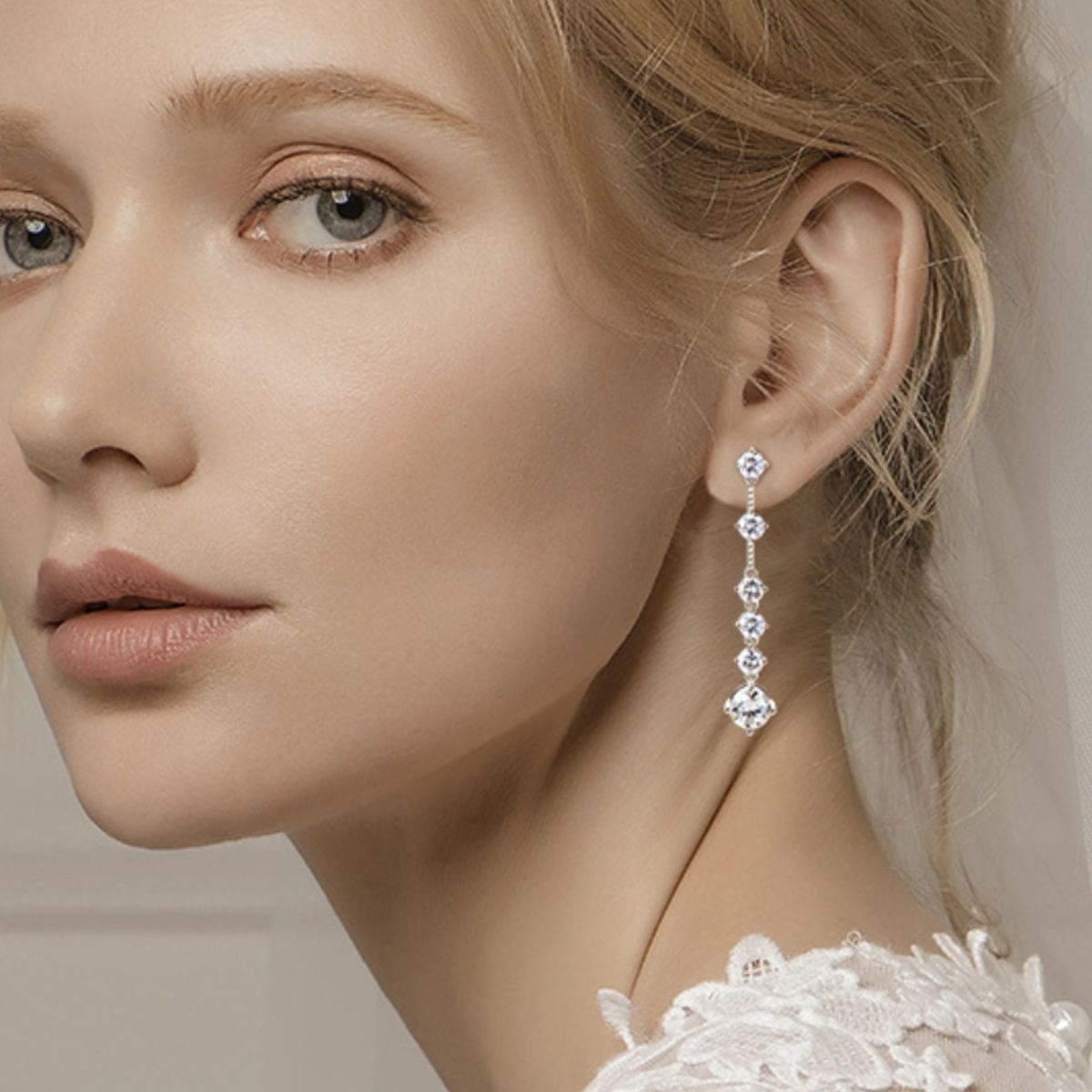 Blonde bride wearing a lace wedding dress with 4-carat environmentally friendly Moissantie drop earrings set in 925 Sterling silver. 5 smaller gems down the drop, with a larger one at the bottom.