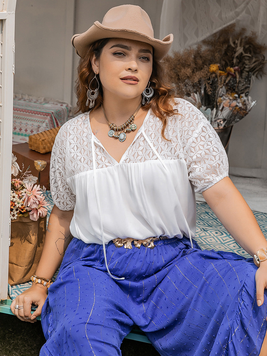 Red haired model wearing a white plus size tie neck short sleeve blouse with lace detailing on the shoulders and sleeves.