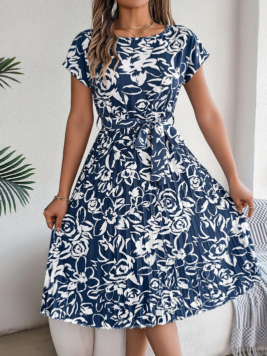 Blonde model wearing a short sleeve, dark blue and white printed dress with a tie waist and midi length.