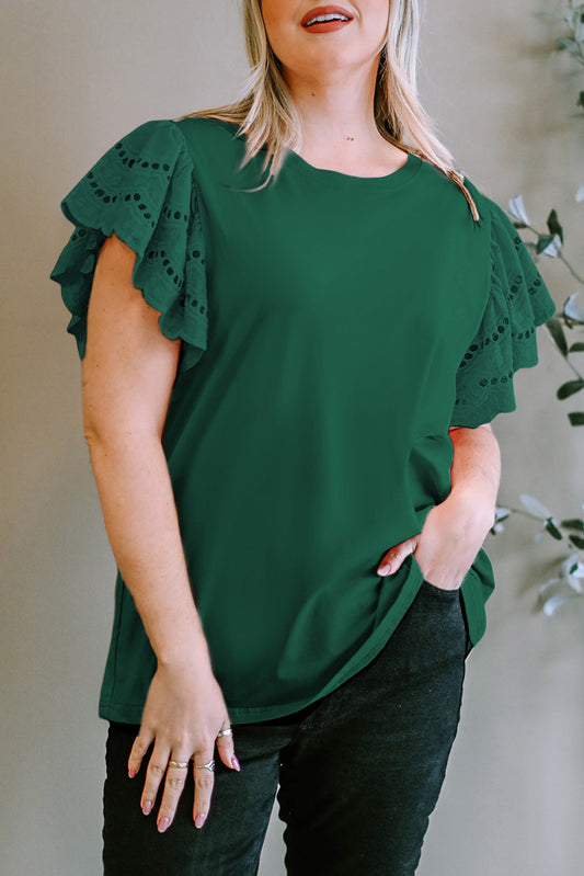 Blonde woman wearing a green eyelet flutter sleeve blouse against a light tan backdrop. Available in multiple colors