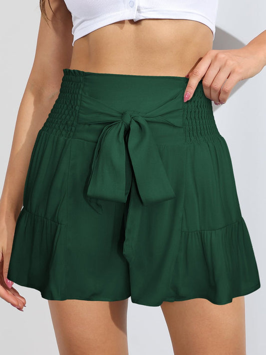 Model wearing a white top with forest green shorts with smocked sides, tie front, and a high waist. Available in several other colors.
