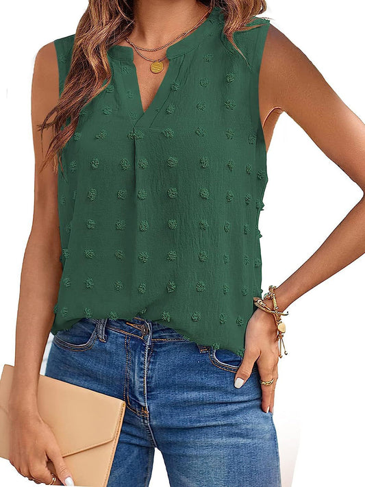 Brunette model wearing jeans and a swiss dot notched tank in green with a tan clutch.