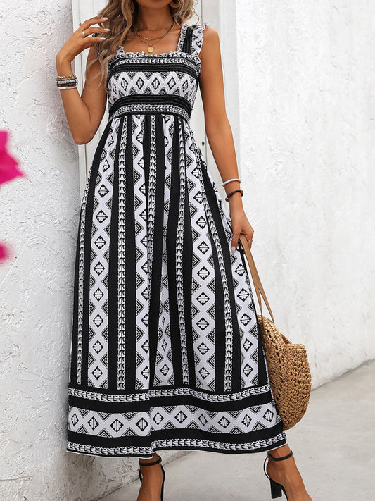 Classic black and white print dress with smocked top, wide straps, and an ankle length skirt worn by a blonde model in front of a white wall.