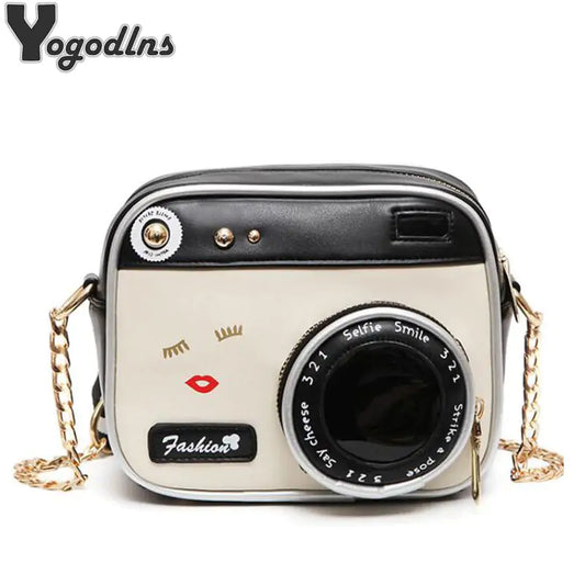Adorable white and black crossbody bag with a gold chain and the look of a 35 mm camera against a white backdop.