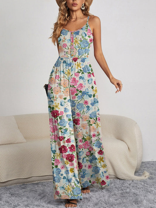 Blonde model wearing a beautiful floral jumpsuit with a button front and spaghetti straps and wide legs in a living room.