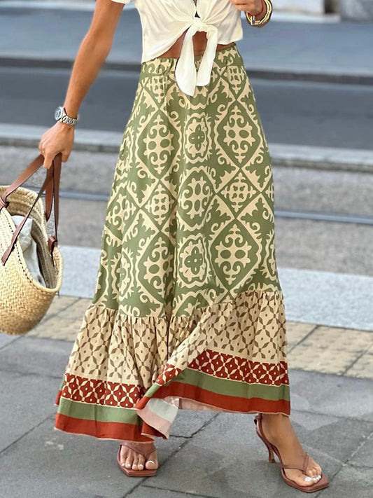 Adorable geometric patterned maxi skirt in matcha green, ivory, and terracotta with a peasant style, worn but a model wearing an ivory tie top on a city street.