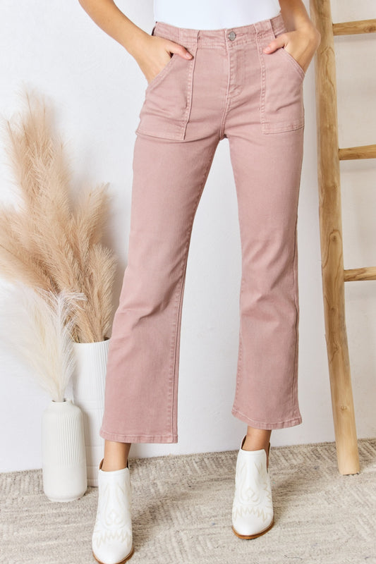 Model wearing blush high rise ankle flare jeans with white booties against a white background.