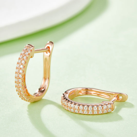 Rose gold hoop earrings with two layers of Moissanite against a mint green background.