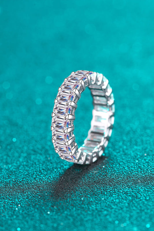 10.5 carat baguette moissanite eternity ring shown on its side on a teal background. 
