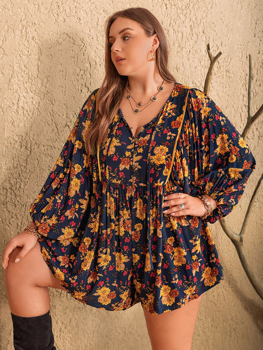 Blonde model wearing a plus size, floral, tie neck balloon sleeve romper om navy with  yellow flowers.
