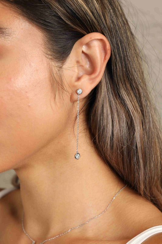 Woman with long brown hair wearing .8 carat each chain earrings with one stone at the top and one at the bottom.