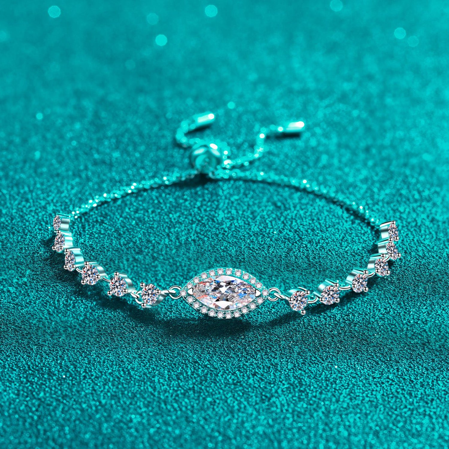 Sterling silver Moissanite bracelet with a one carat stone in the center and 6 smaller stones on each side. Adjustable. Photographed on a teal background.