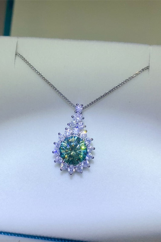 3 carat moissanite necklace with a round green center stone surrounded by smaller white moissanite stones set in sterling silver on a white jeweler's box card.
