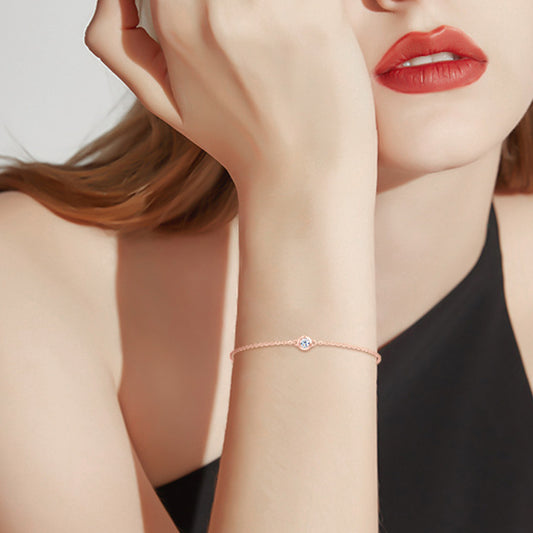 Very delicate adjustable rose gold plated sterling silver Moissanite bracelet on a model wearing a black one-shoulder top and red lipstick with red hair.
