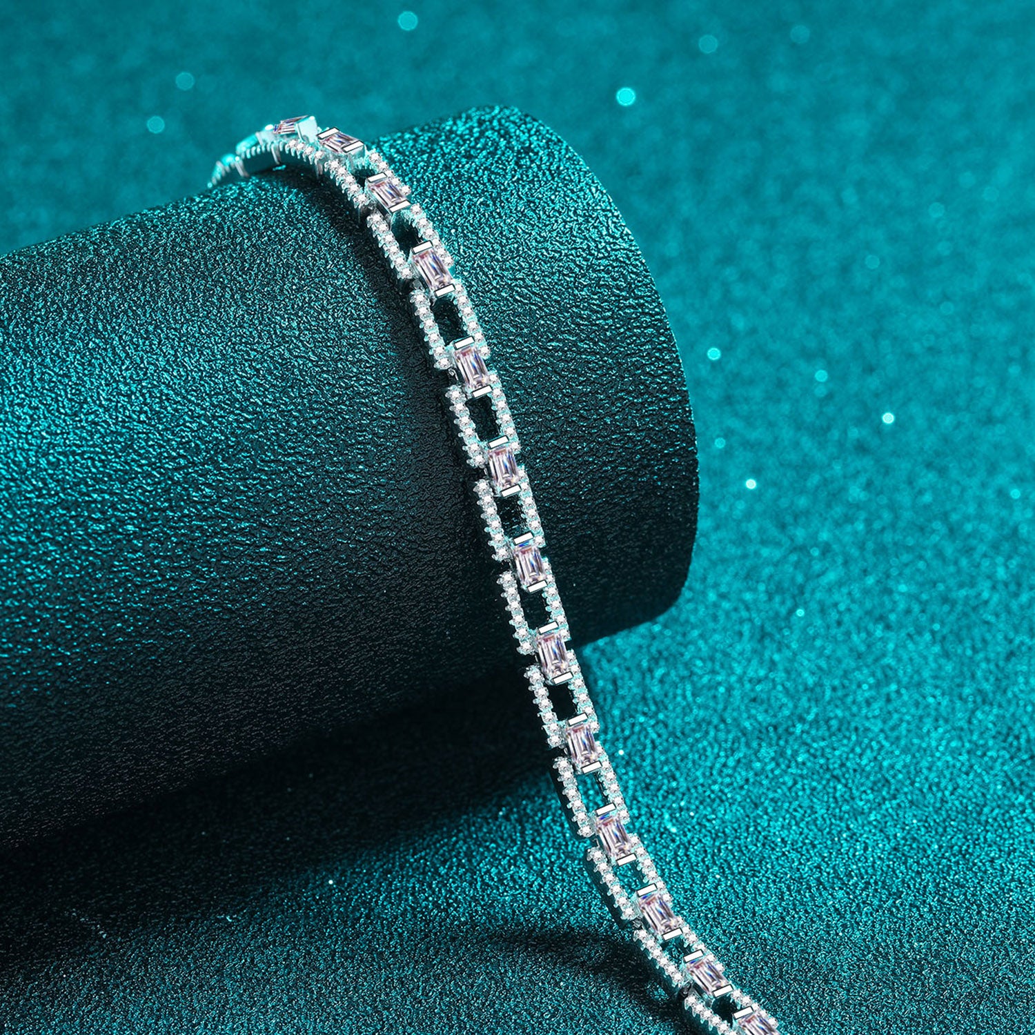 Sterling silver 3.2 carat chain link moissanite bracelet with round and baguette stones on a teal background