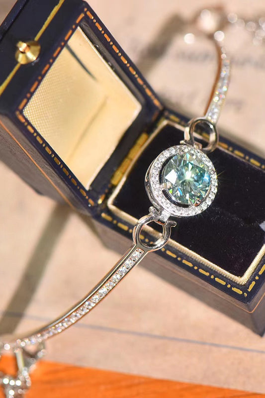 Beautiful 2 carat Moissanite bracelet with a mint green round center Moissanite stone. Shown placed over a jewelry box and a flat surface.